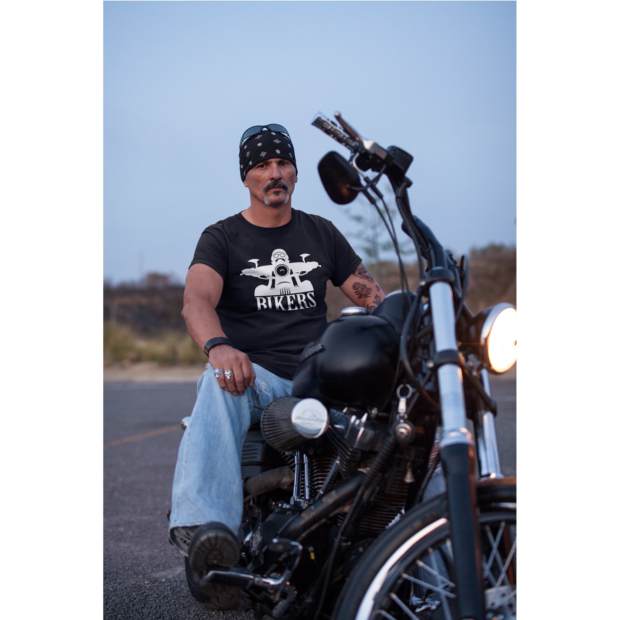 Man sitting on a motorcycle wearing a black t-shirt with a graphic design.
