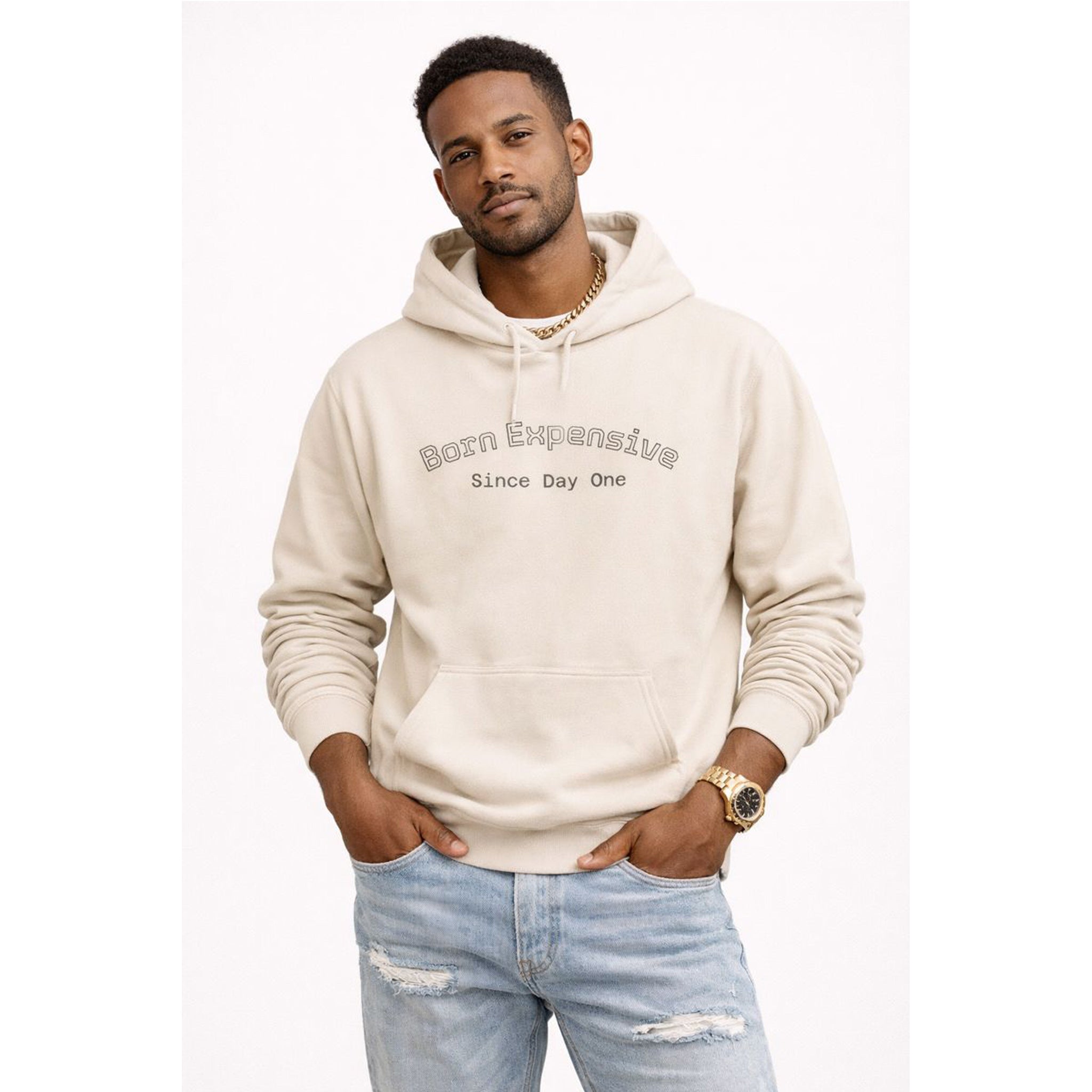 Man wearing a beige hoodie with text and light blue jeans on a white background