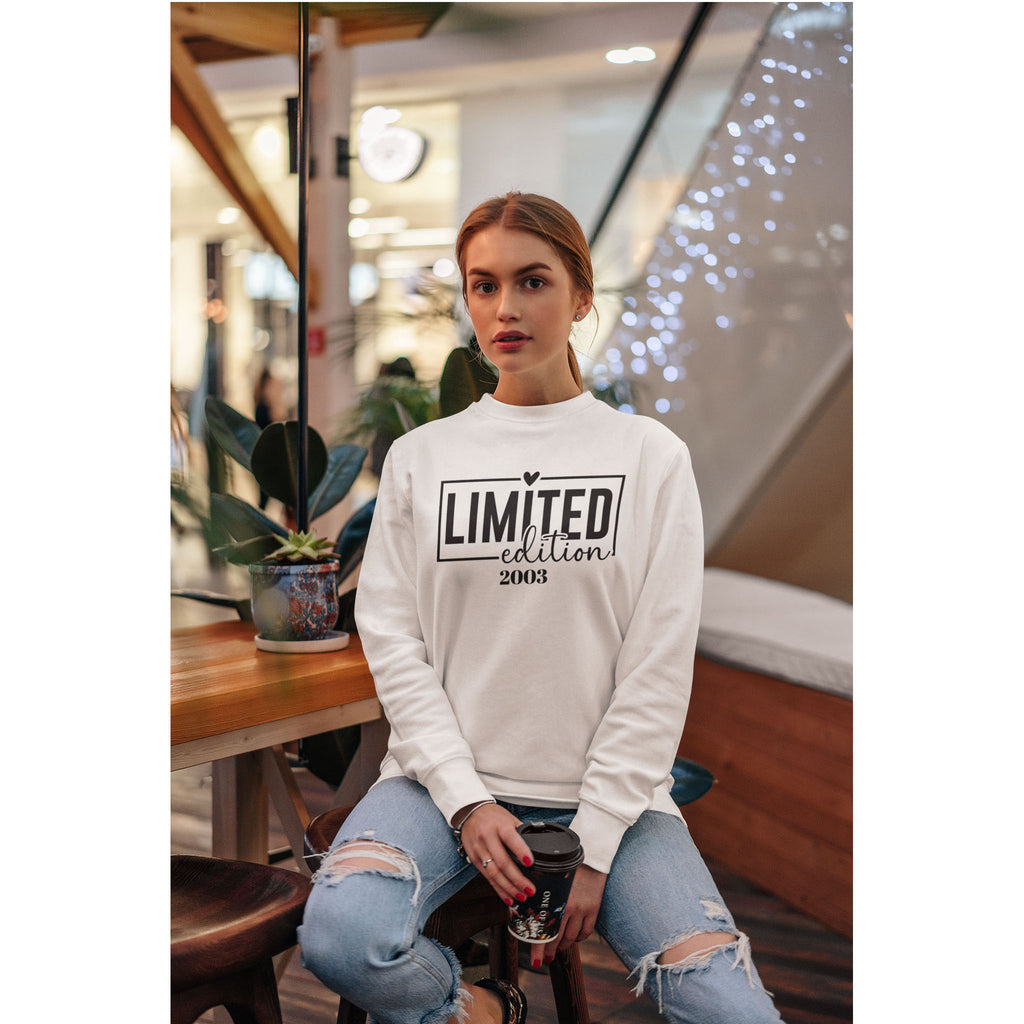 Person wearing a white sweatshirt with 'Limited Edition 2003' text, sitting in a casual setting.
