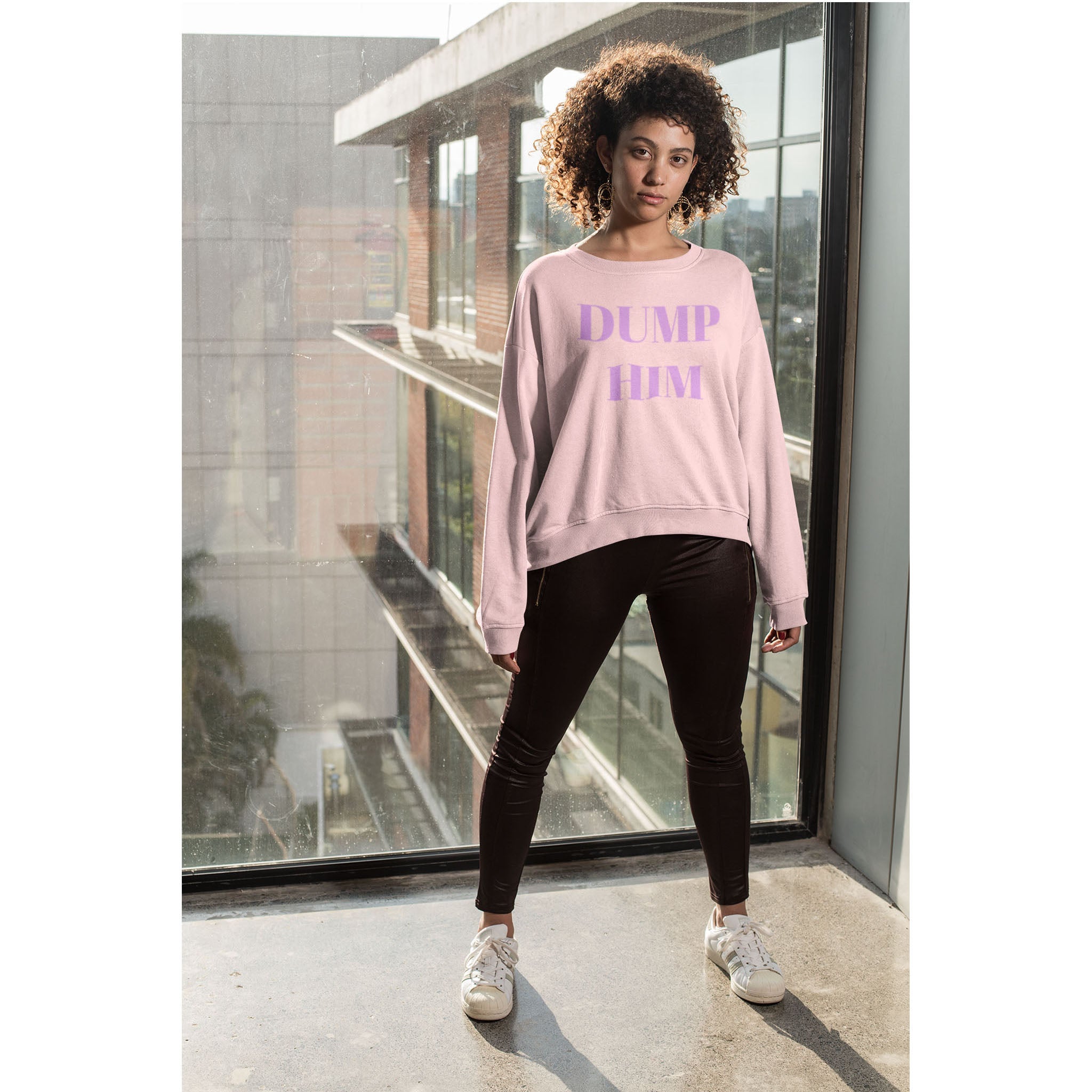 Person wearing a pink sweatshirt with 'DUMP HIM' text in a modern building setting