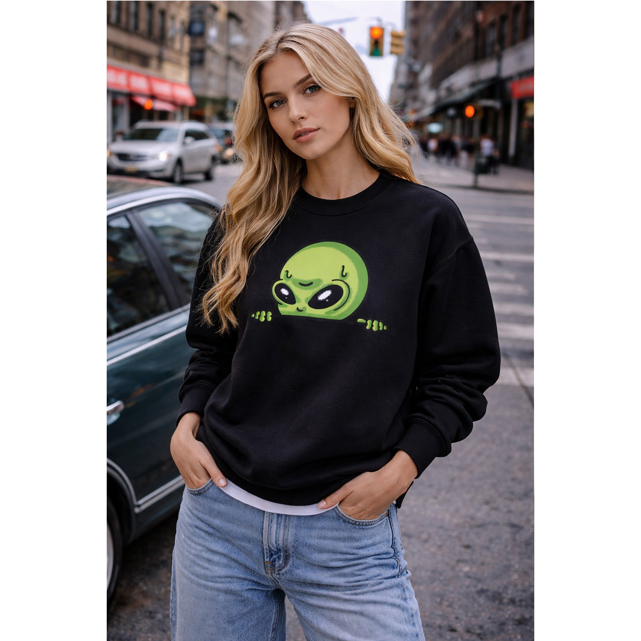 Woman wearing a black sweatshirt with a green alien design on a city street – Bamerix