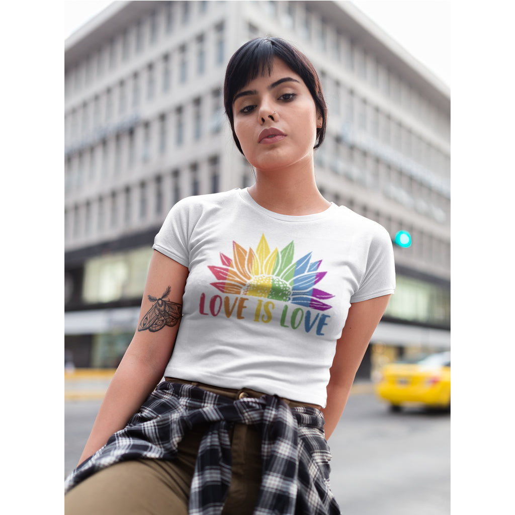 Woman wearing a white t-shirt with a rainbow-colored 'LOVE IS LOVE' design in an urban setting.