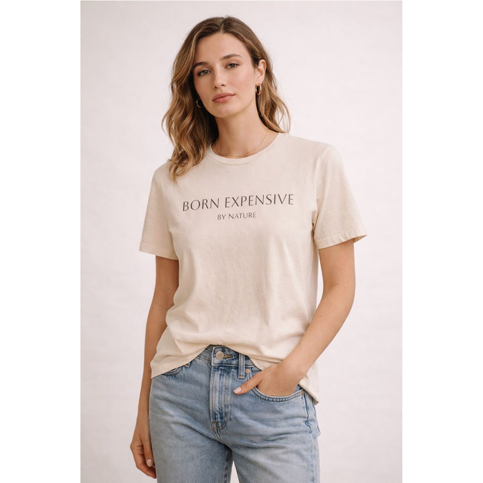 Woman wearing a beige t-shirt with text, standing against a plain background