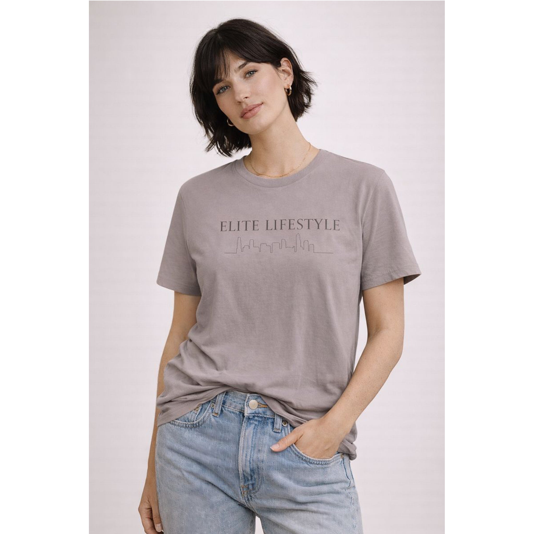 Woman wearing a gray t-shirt with 'ELITE LIFESTYLE' text on a light pink background