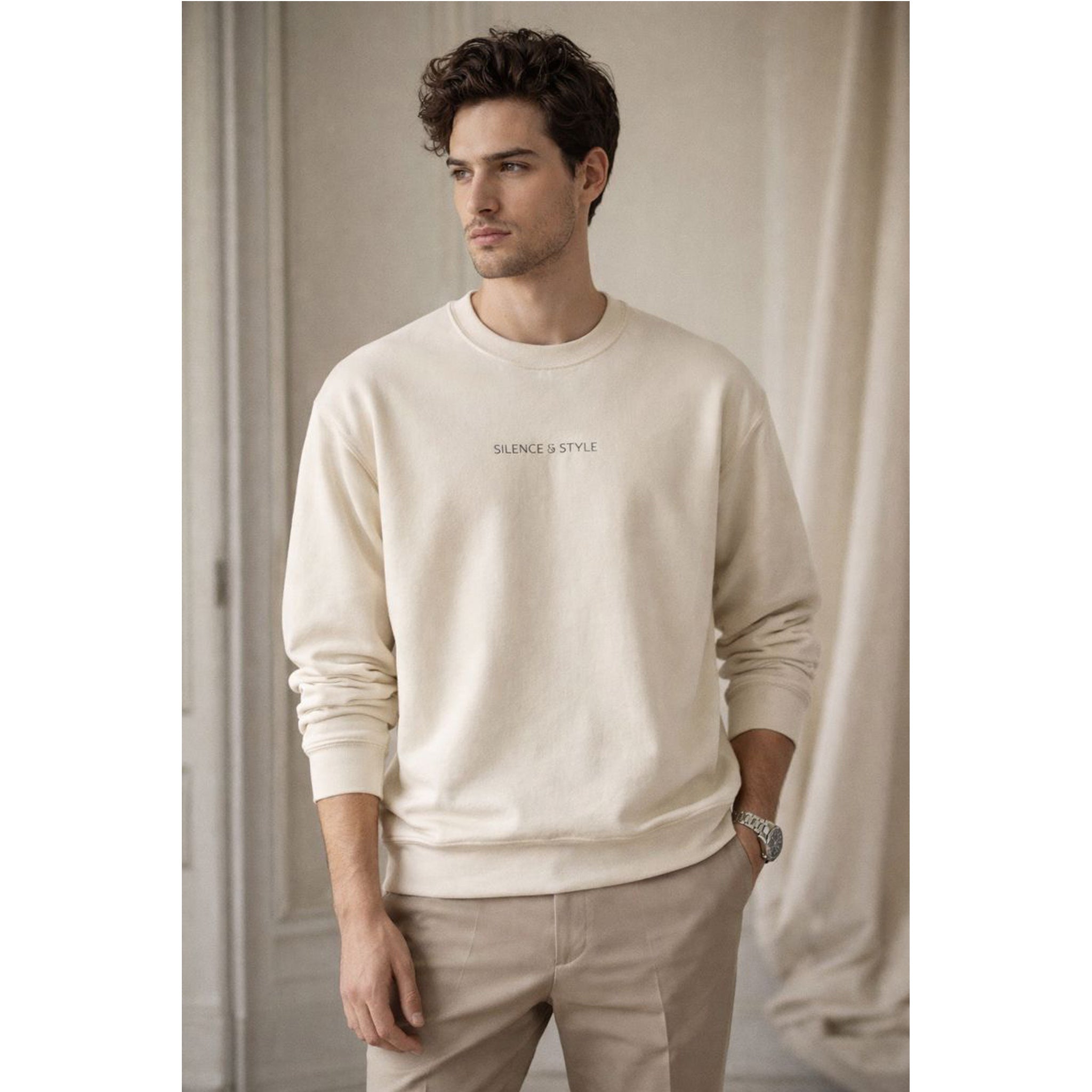 Man wearing a beige sweatshirt with text, standing against a neutral background