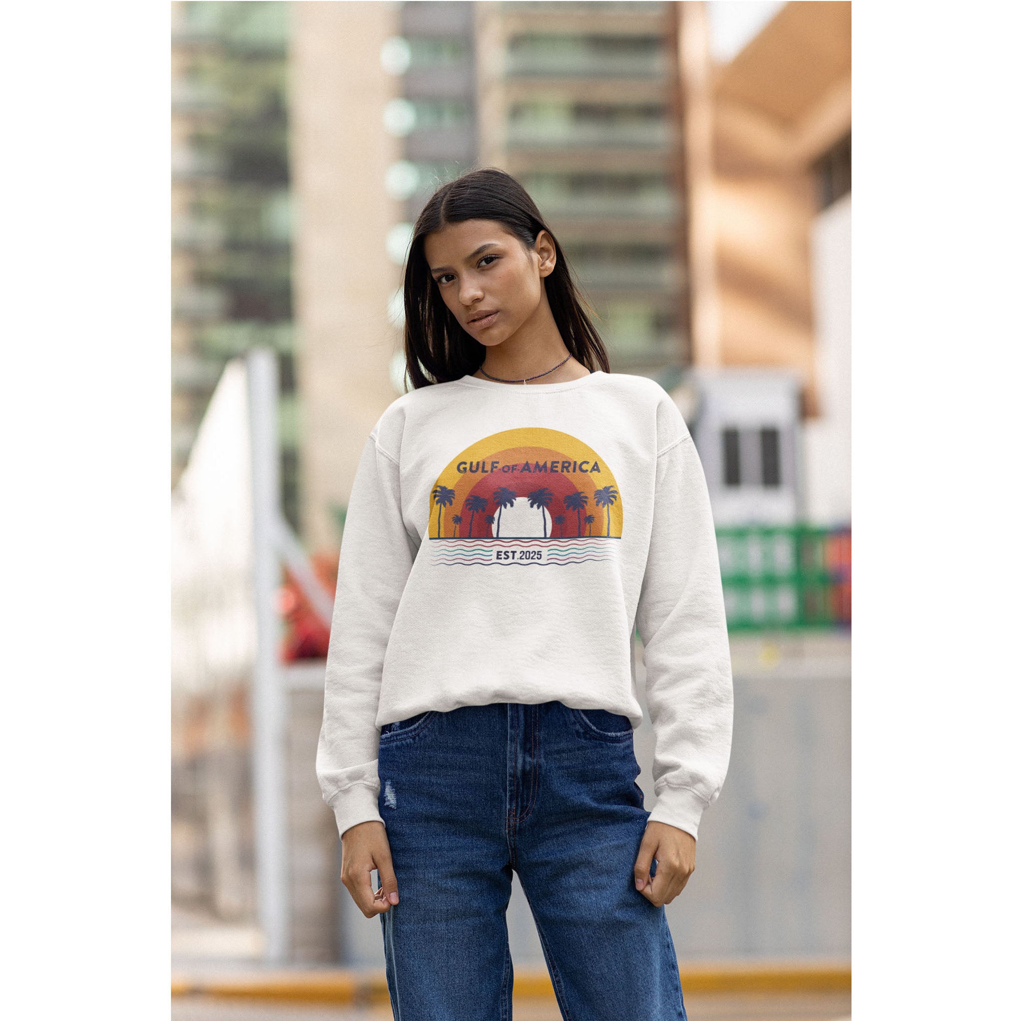 Woman wearing a white sweatshirt with a graphic design, standing outdoors.