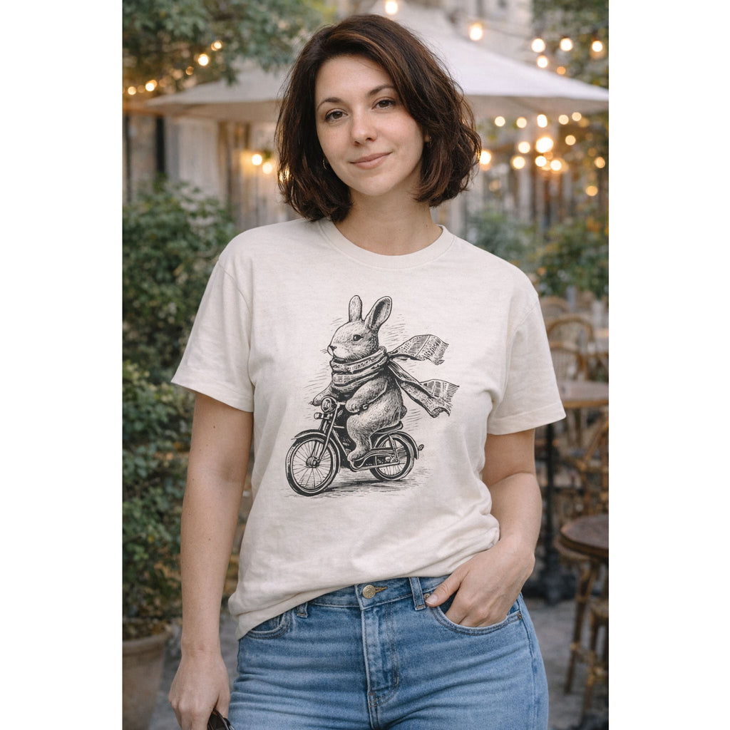 Person wearing a white t-shirt with a graphic of a rabbit riding a bicycle, standing outdoors – Bamerix