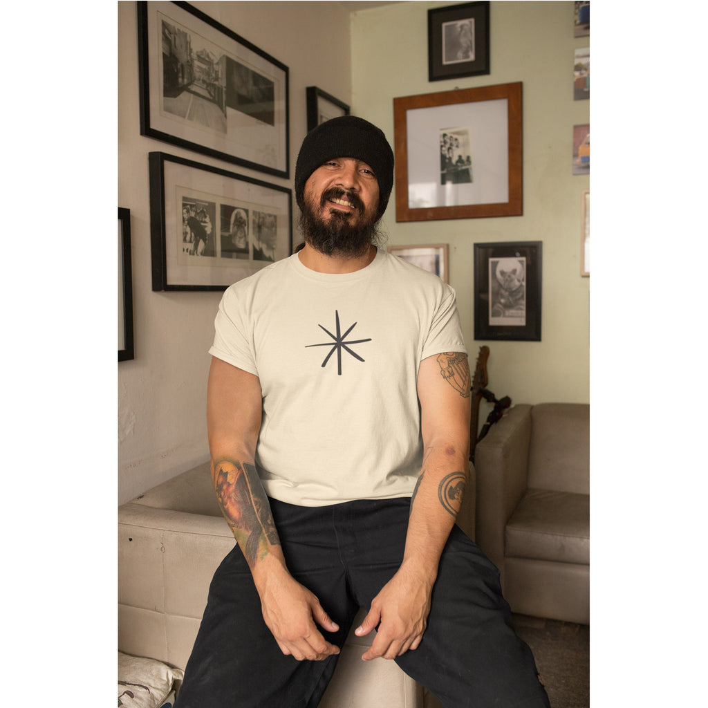 Man sitting in a living room wearing a white t-shirt with a black symbol