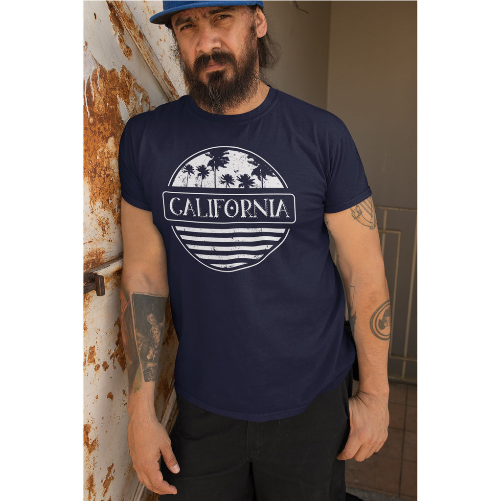 Man wearing a navy blue t-shirt with 'California' design leaning against a wall.
