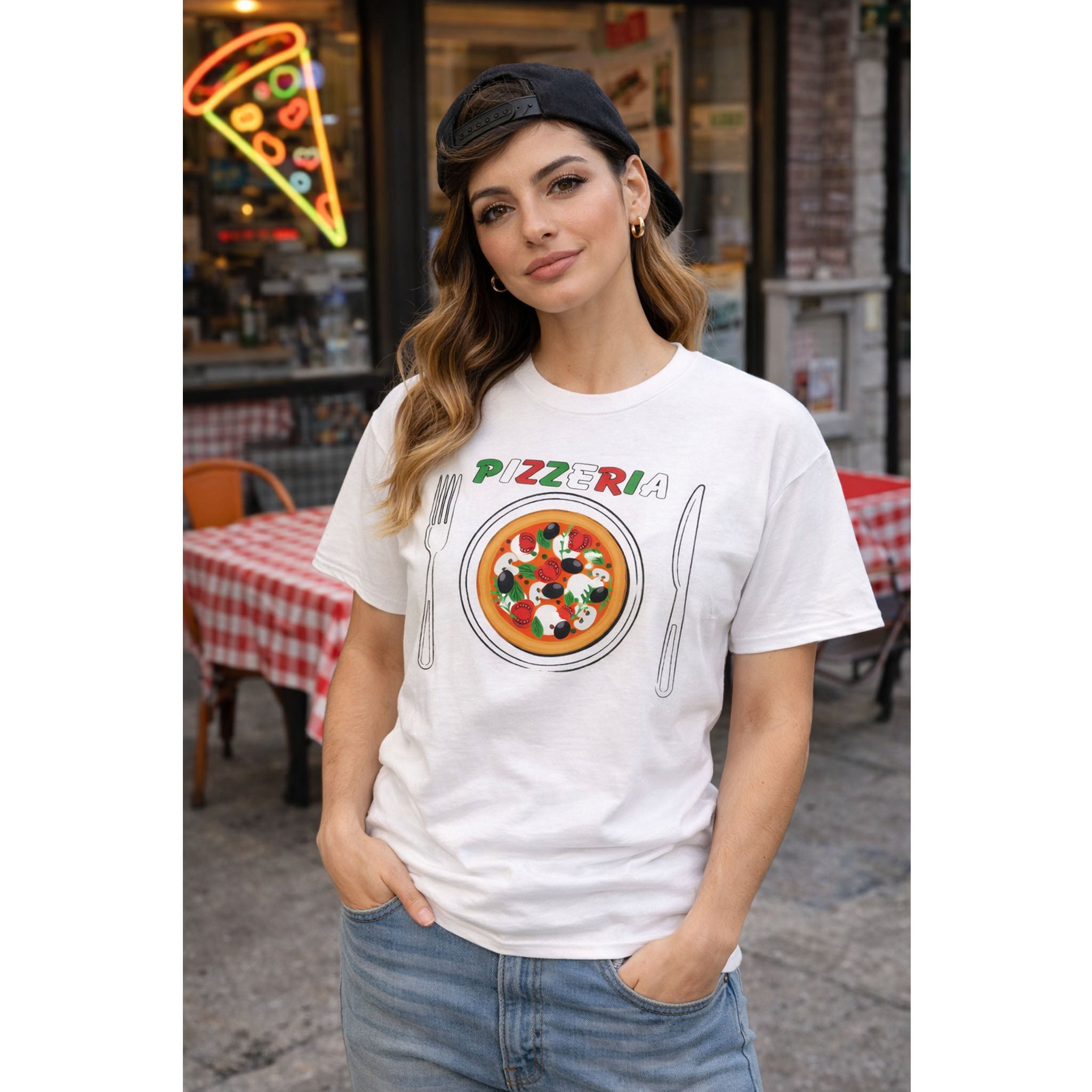 Woman wearing a 'Pizzeria' themed t-shirt in front of a pizzeria.