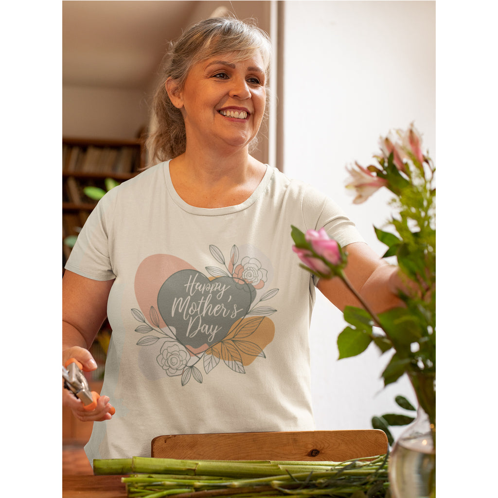 Woman wearing a 'Happy Mother's Day' t-shirt, arranging flowers indoors.