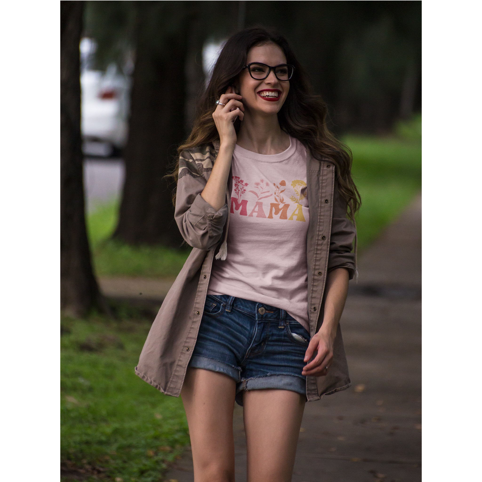 Woman in a park wearing a 'MAMA' t-shirt and denim shorts.