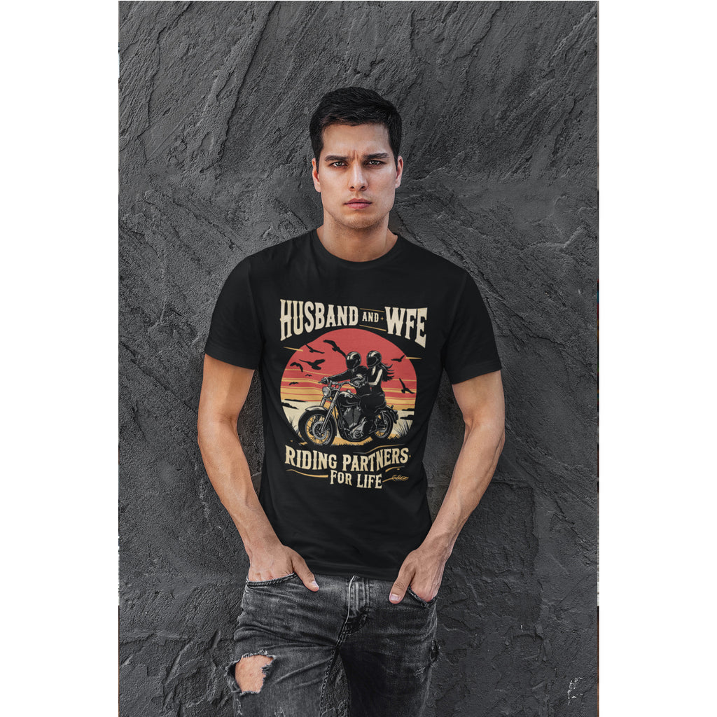 Man wearing a black t-shirt with a graphic design and text, standing against a dark textured wall.