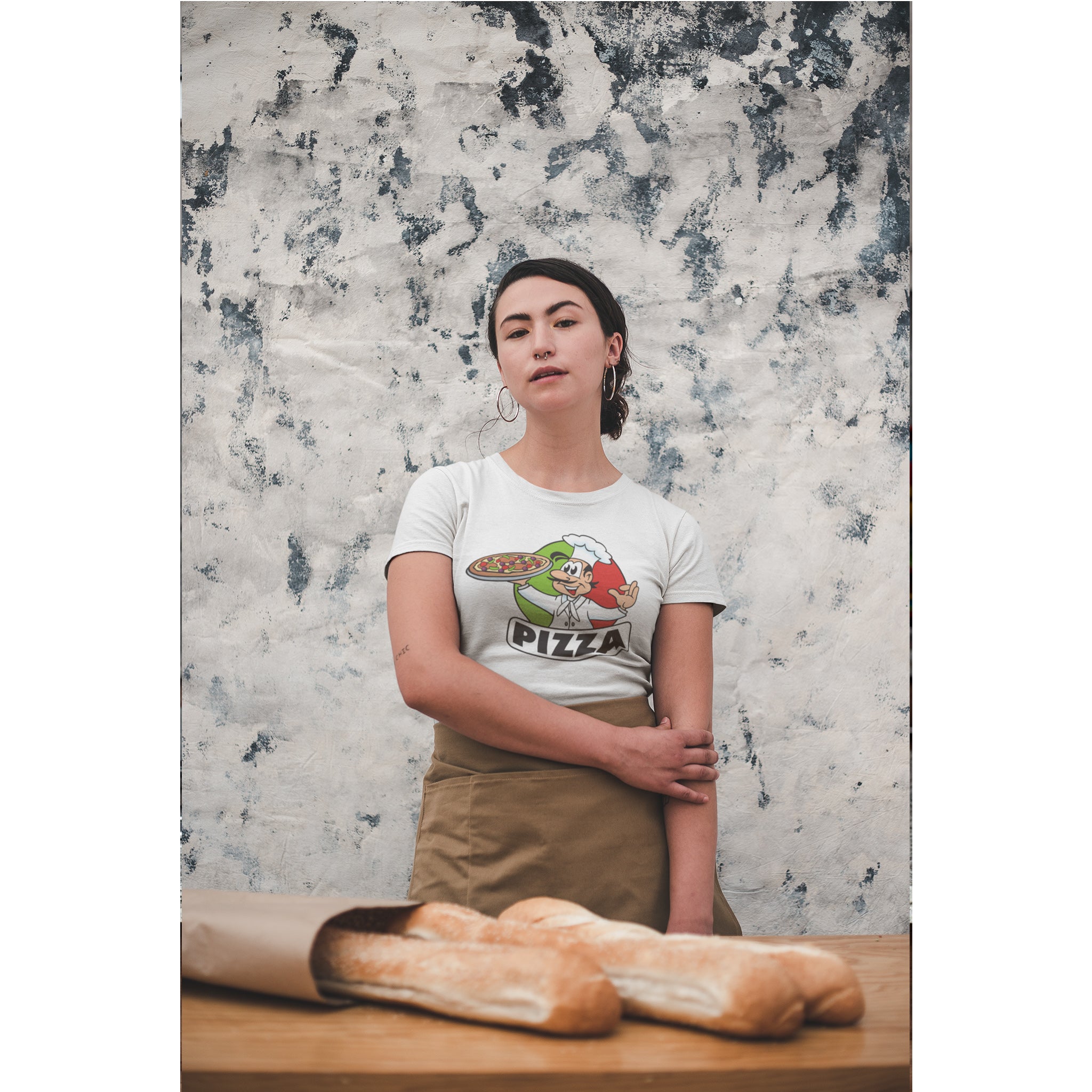 Person wearing a t-shirt with a pizza graphic in front of a marble wall.