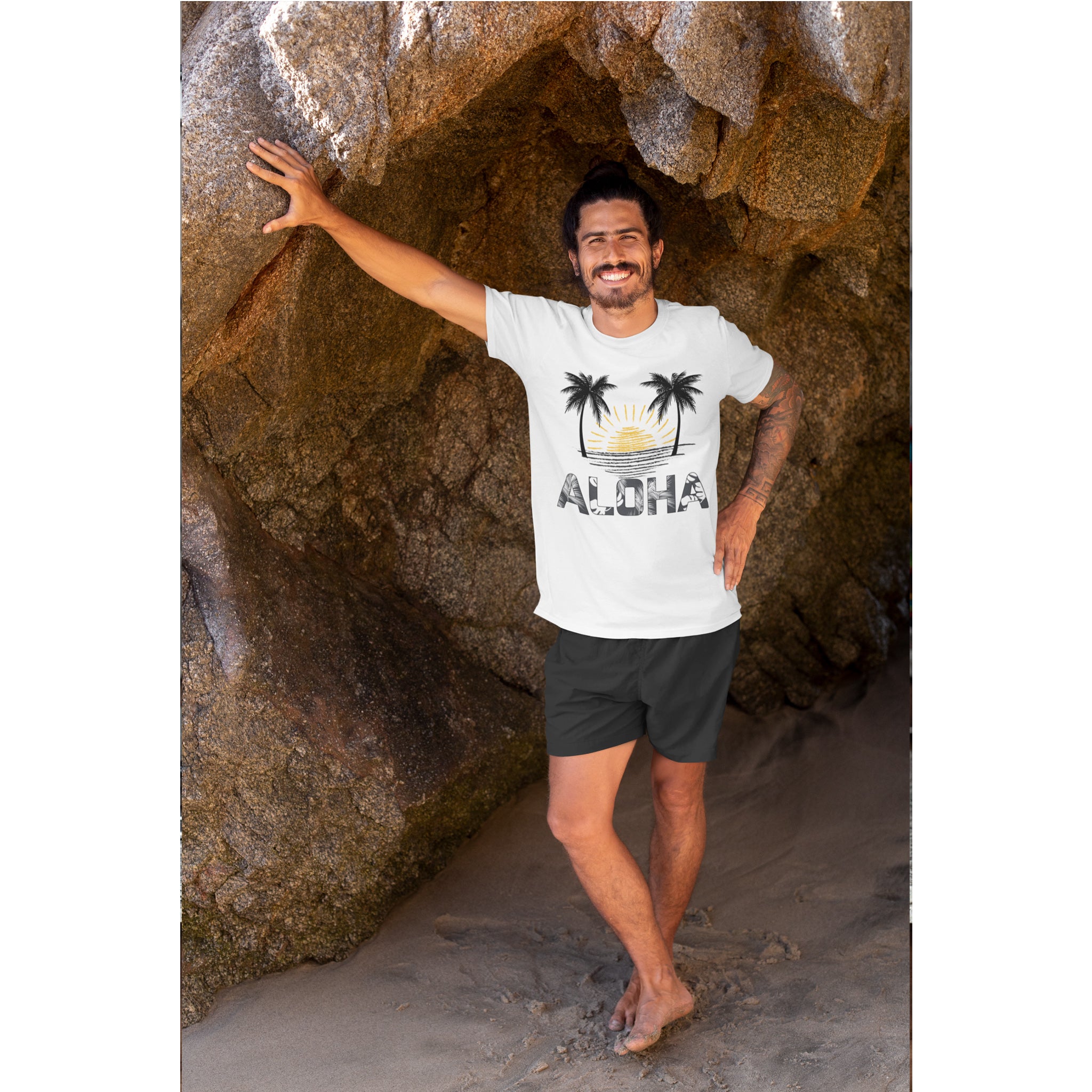 Man wearing a white t-shirt with a palm tree design and 'Aloha' text, standing in a rocky cave.