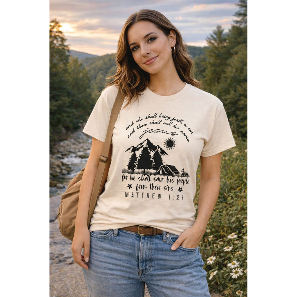 Woman wearing a t-shirt with a nature-themed design and text, standing outdoors.