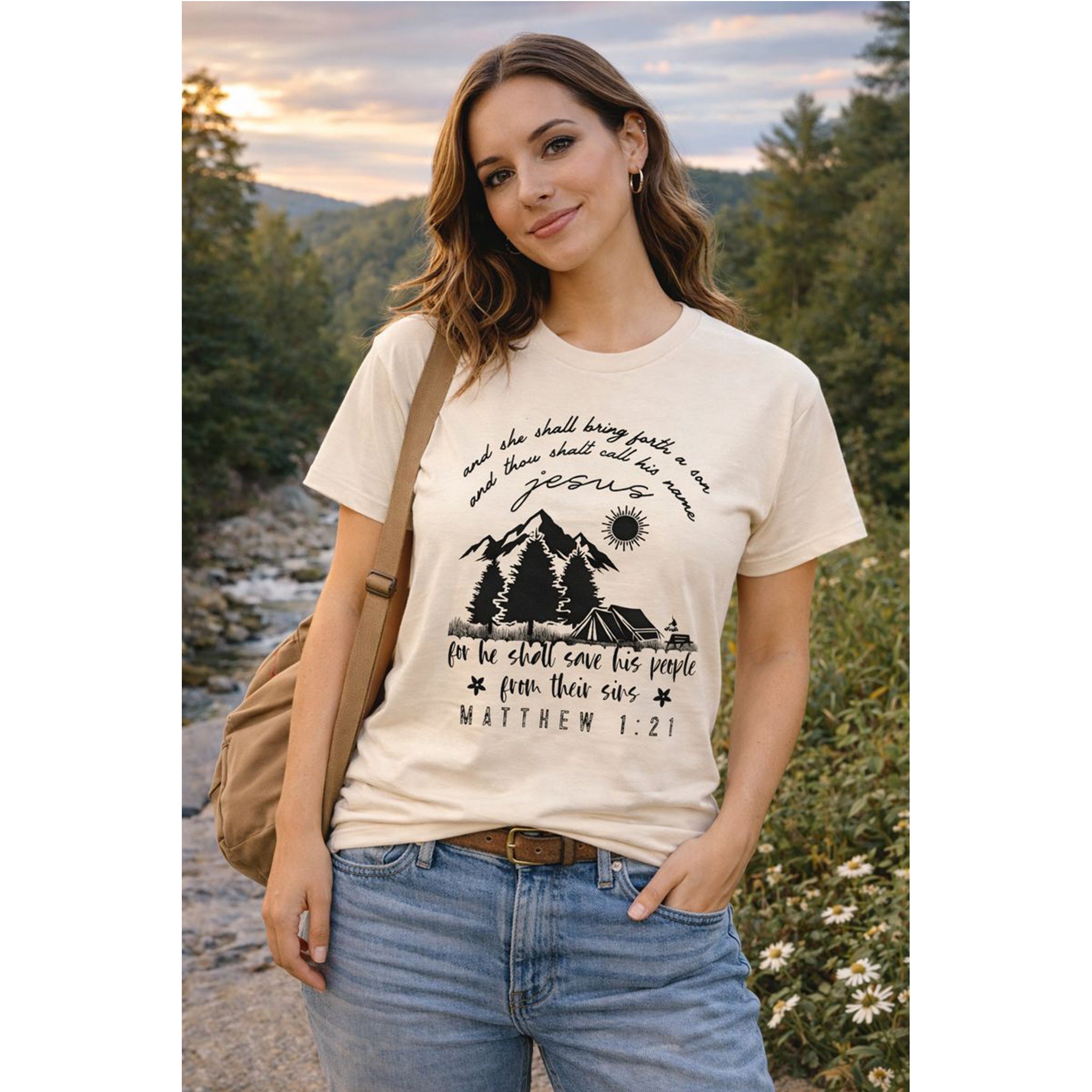 Woman wearing a t-shirt with a nature-themed design and text, standing outdoors.