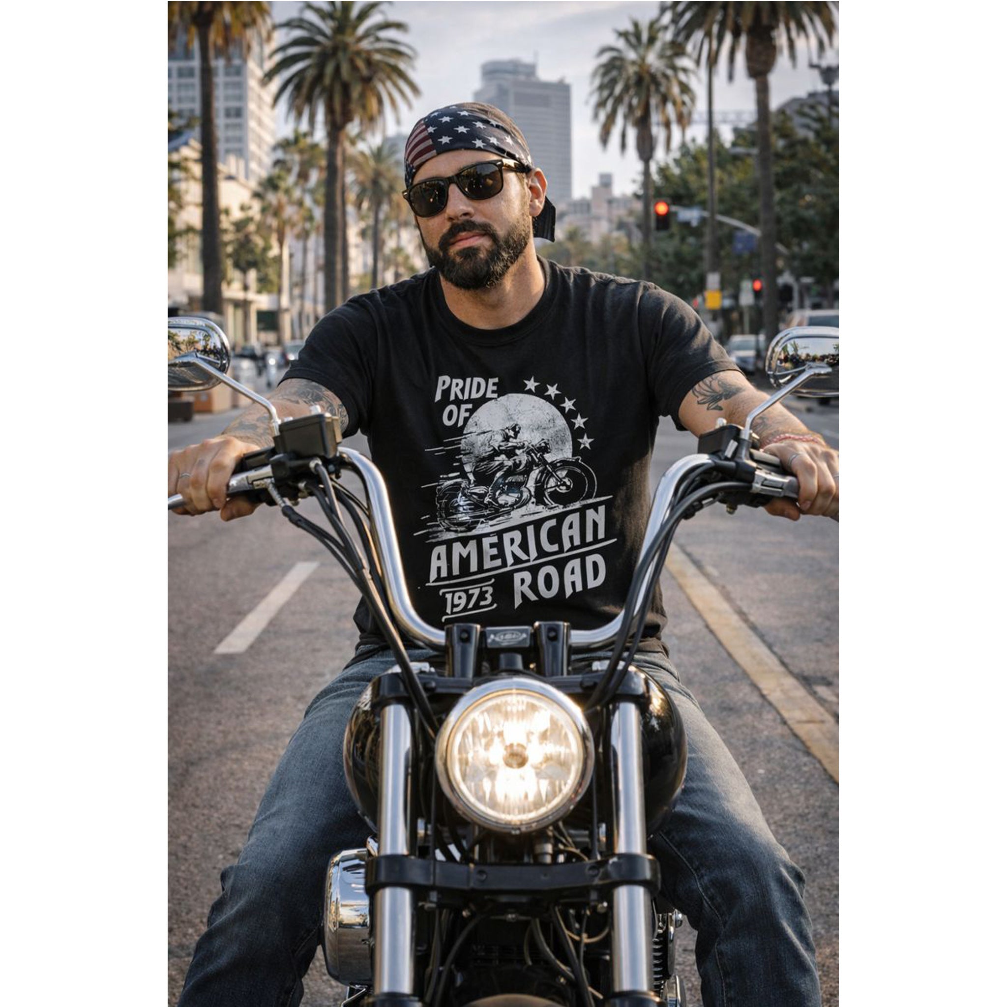 Man riding a motorcycle wearing a black t-shirt with 'Pride of American Road' design.