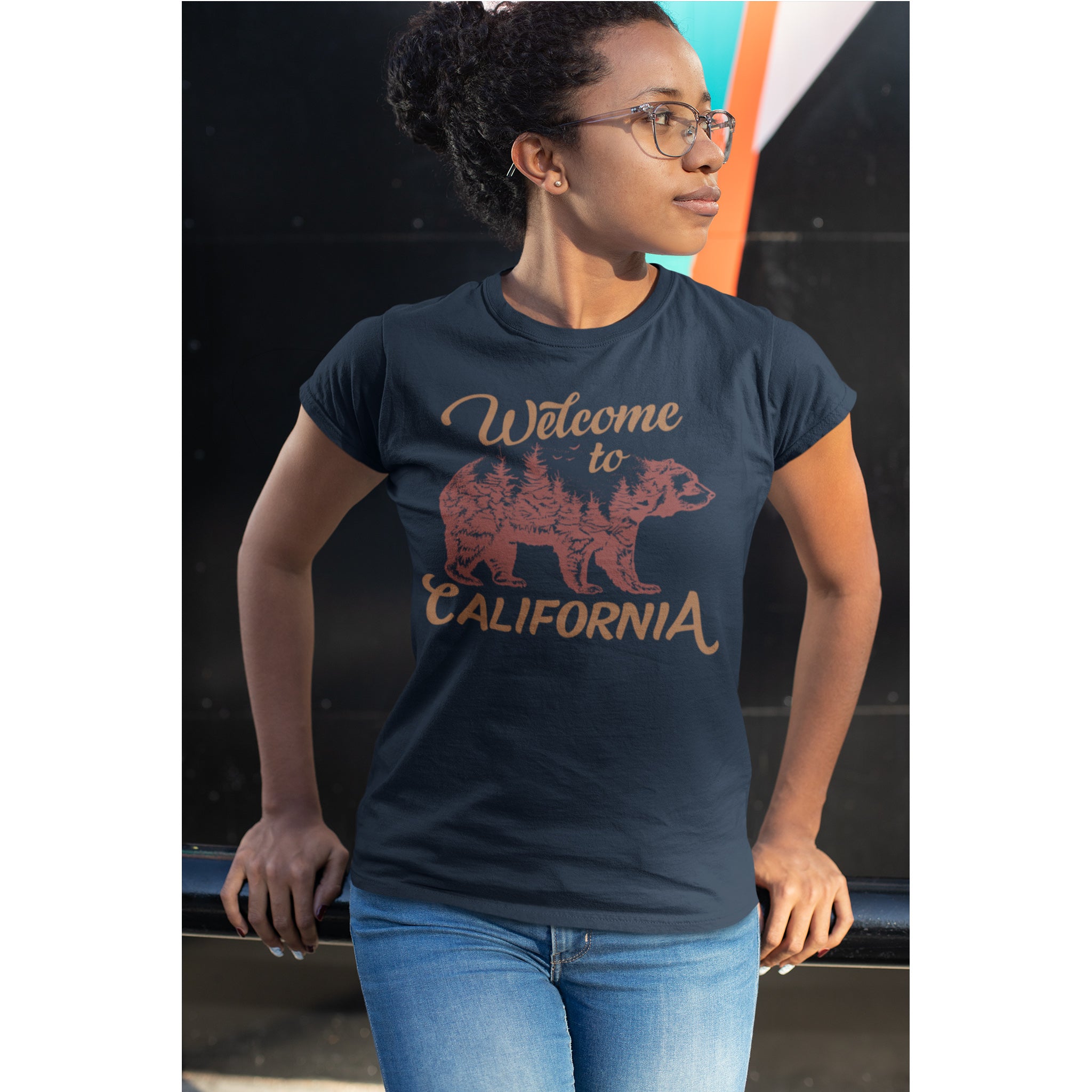 Woman wearing a navy t-shirt with 'Welcome to California' graphic design.