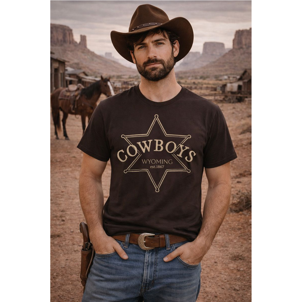 Man wearing a 'Cowboys Wyoming' t-shirt in a desert setting with horses.