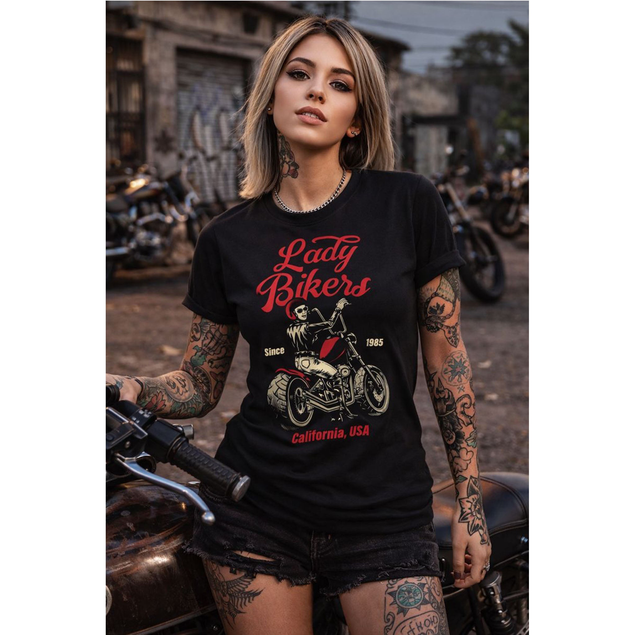 Woman wearing a 'Lady Bikers' t-shirt with tattoos and a motorcycle graphic, standing next to a motorcycle.