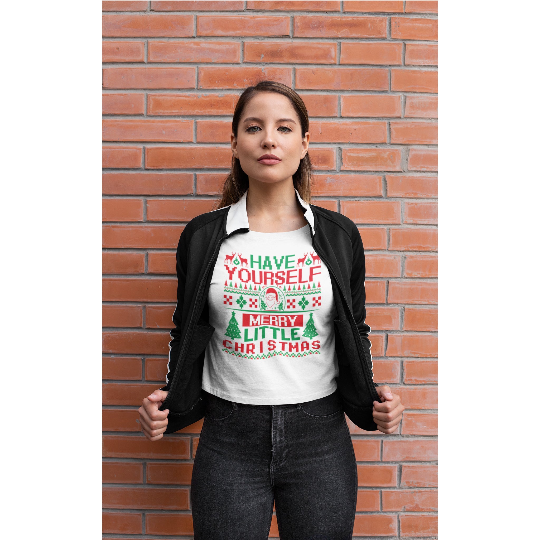 Woman wearing a festive Christmas-themed t-shirt against a brick wall.