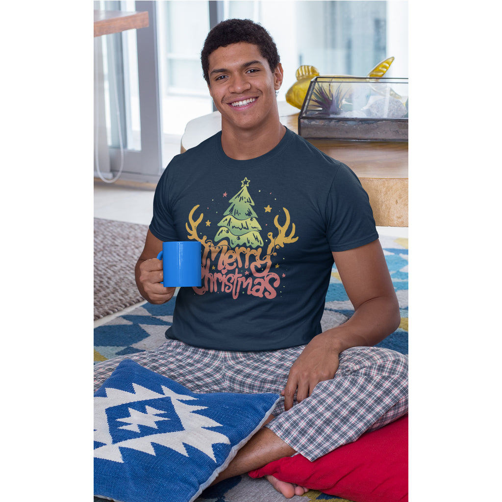 Man wearing a Christmas-themed t-shirt and holding a mug, sitting on a bed.