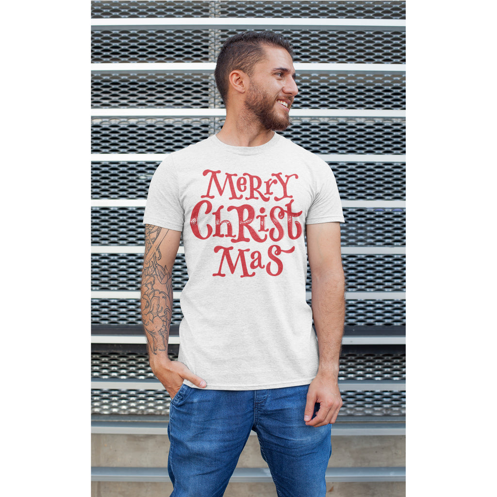 Man wearing a white t-shirt with 'Merry Christ Mas' in red text against a metal wall.