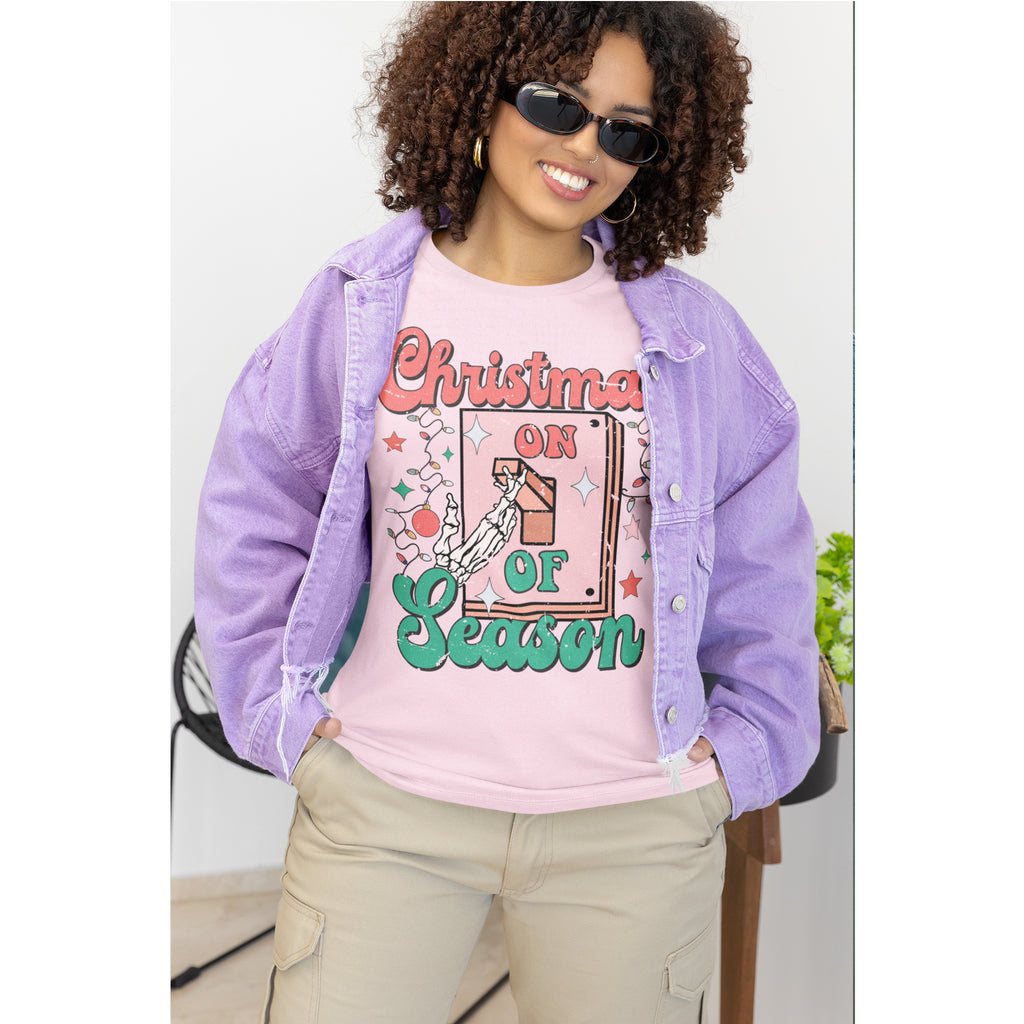 Woman wearing a pink 'Christmas on Season' t-shirt with a purple denim jacket.