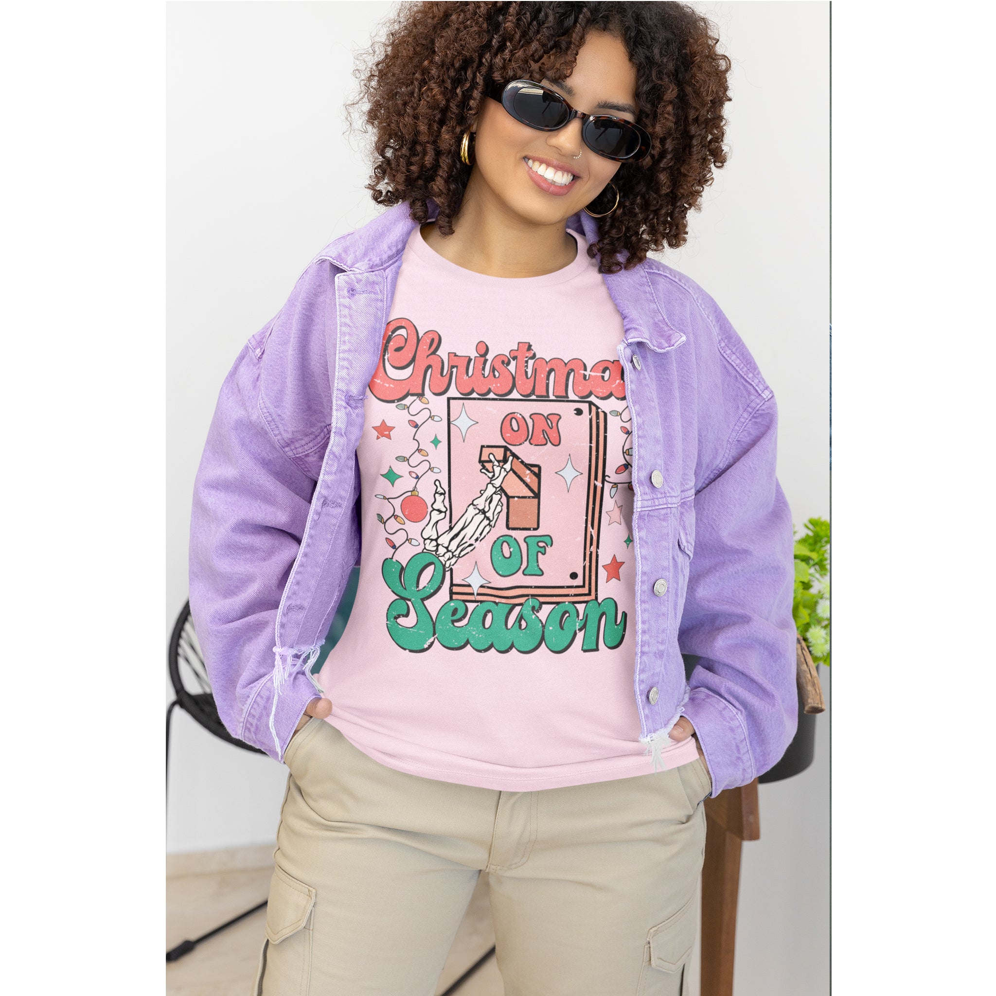 Woman wearing a pink 'Christmas on Season' t-shirt with a purple denim jacket.