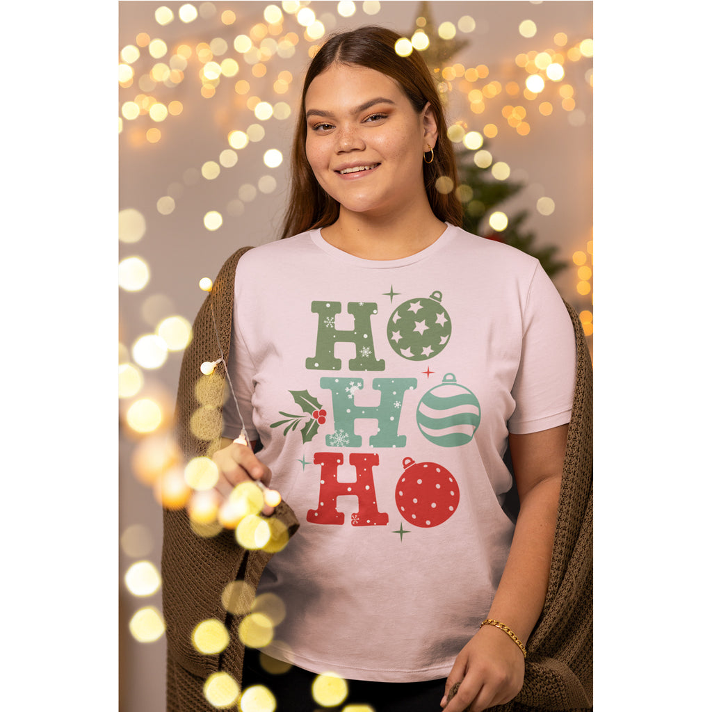 Woman wearing a 'HO HO HO' Christmas-themed t-shirt with festive lights in the background