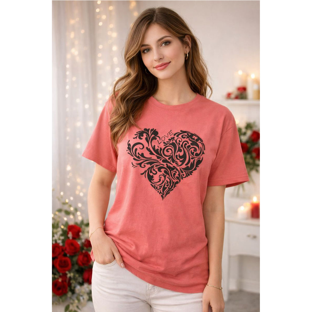 Woman wearing a coral t-shirt with a black heart design in a decorated room.