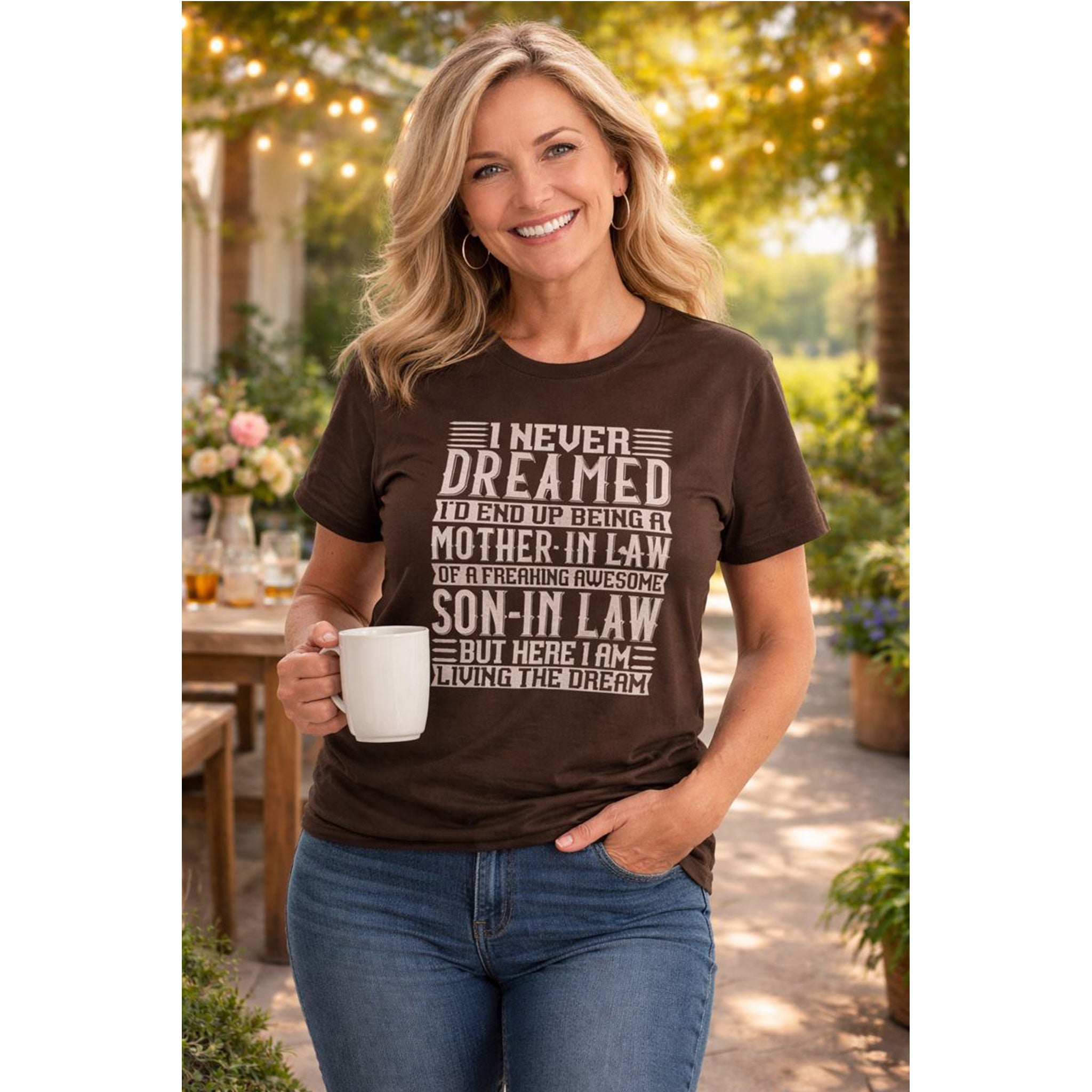 Woman wearing a brown t-shirt with a humorous text design, holding a mug outdoors.